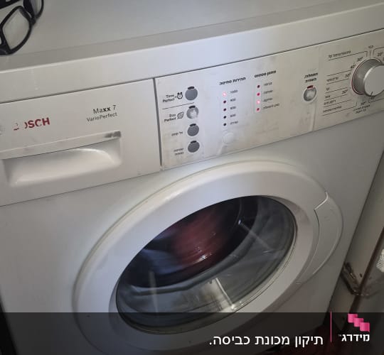 מכונת כביסה עם כוס קפה ומשקפיים על המכסה